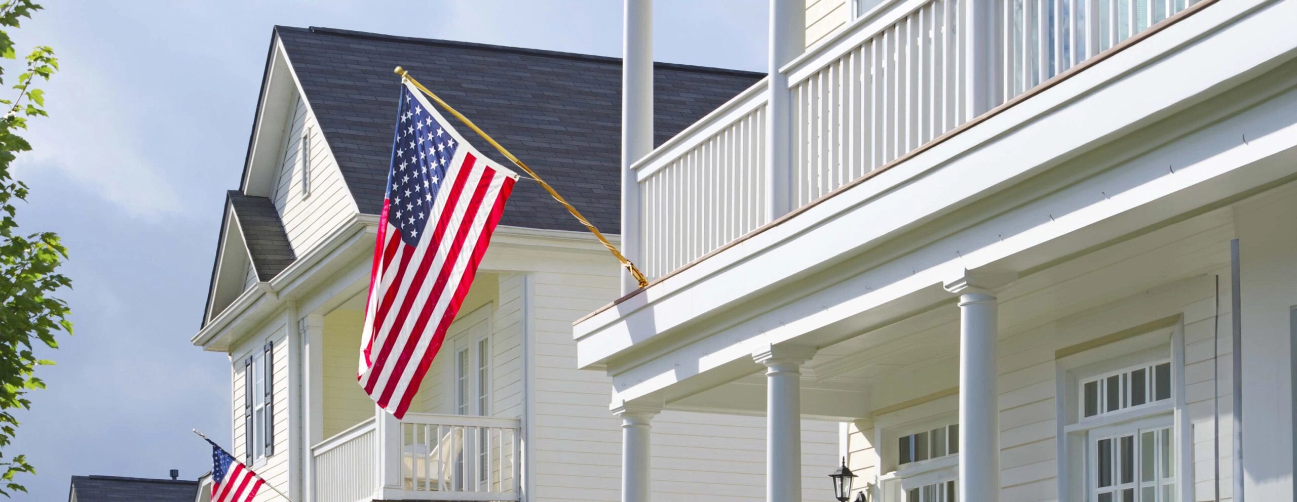 American flag displayed on the front porch of a traditional suburban home, symbolizing community and stability for the FHLBNY 2024 Report to Members